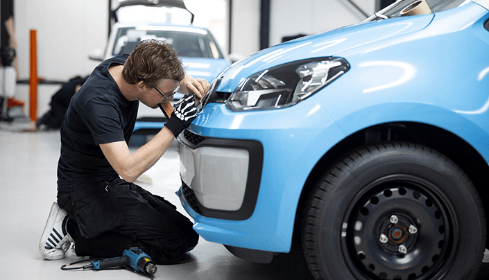 Mechanic repairing the headlight on a vehicle at Ten Minute Oil Change