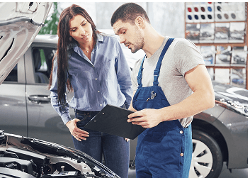 Customer and mechanic reviewing service details by an open hood