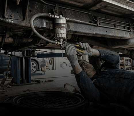 Mechanic replacing a fuel filter under a vehicle