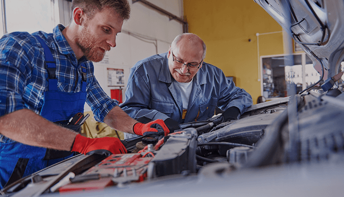 Mechanics inspecting a car engine during battery maintenance service