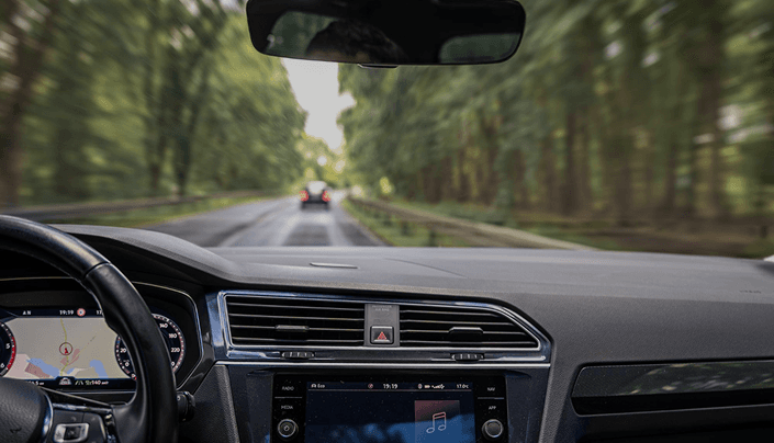 Driver view inside a car showing dashboard and road ahead through the windshield