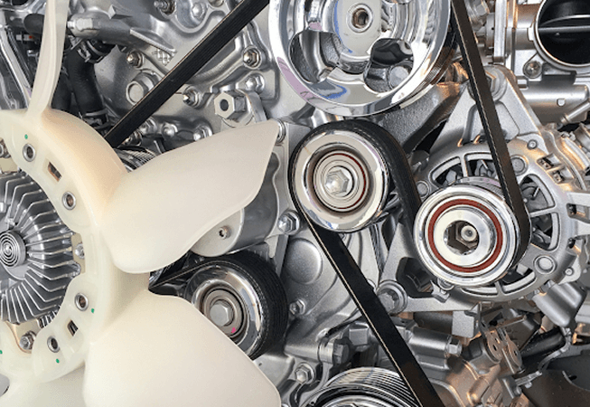 Close-up of a car engine showing the serpentine belt around metal pulleys