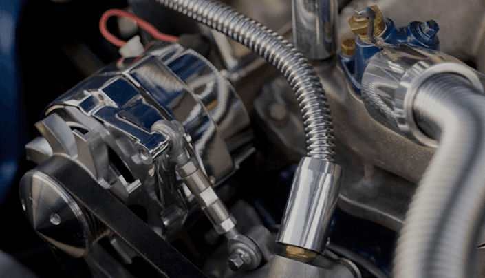 Close-up of chrome engine pulleys, belt, and braided metal hose