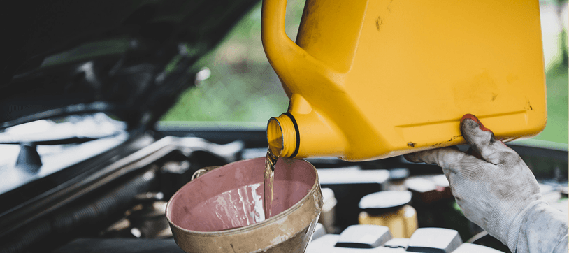Mechanic pouring coolant fluid into a car engine with a funnel
