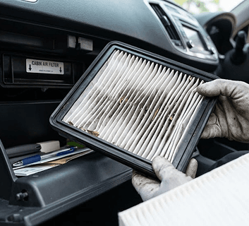 Technician removing a dirty cabin air filter from a vehicle