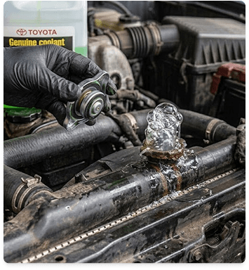 Gloved hand holding a radiator cap over an open radiator