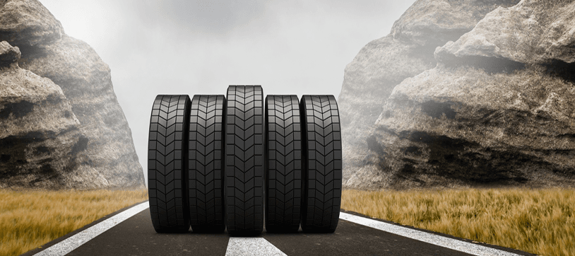 Row of new tires standing on a road with rock formations in the background