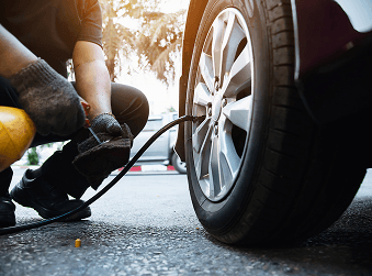 Technician checking tire air pressure on a car