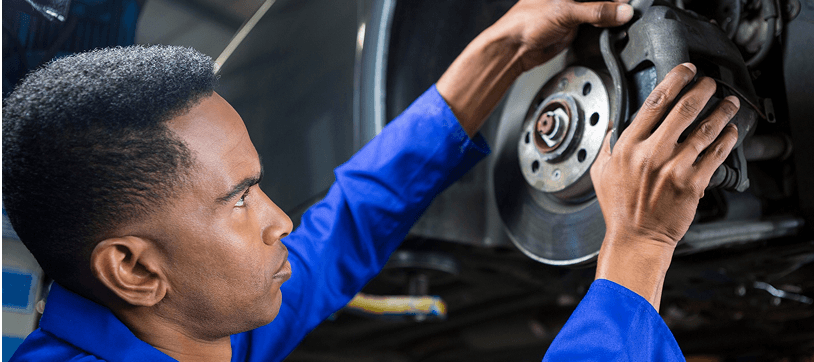 Technician in a blue shirt working on a car disc brake assembly