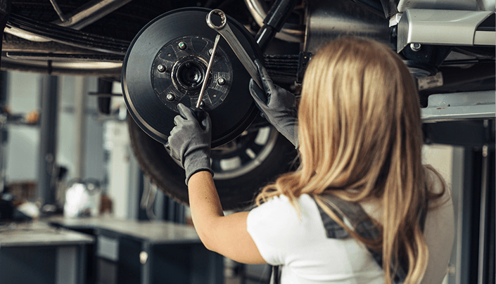 Technician working on a vehicle wheel and brake assembly on a lift