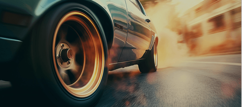 Close-up of a car wheel with gold rim and tire smoke during braking