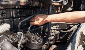 Technician working on fuel system components in an engine bay