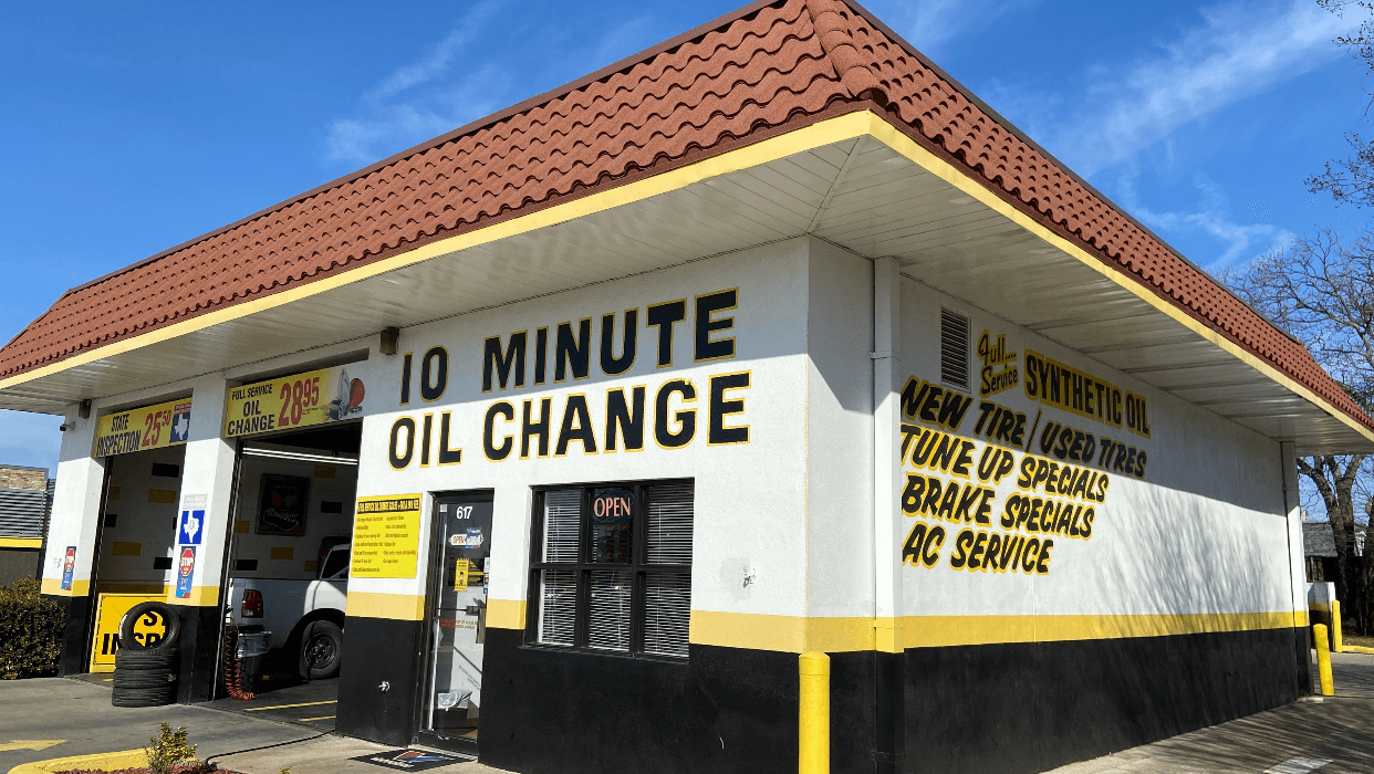 Mechanic smiling while servicing a vehicle at Ten Minute Oil Change Plano