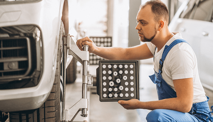 Mechanic performing wheel alignment on a vehicle