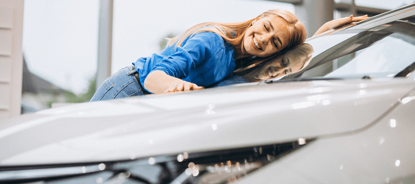 Smiling woman leaning on a white car at Ten Minute Oil Change in Garland