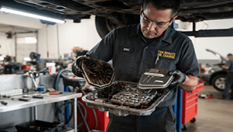 Mechanic holding a dirty transmission oil pan