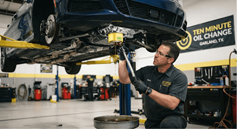 Mechanic servicing a vehicle raised on a lift at Ten Minute Oil Change