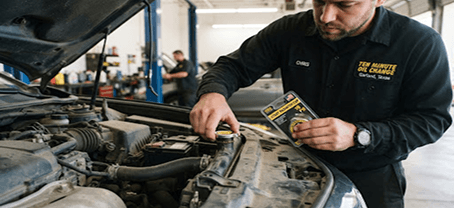 Mechanic replacing a radiator cap under an open hood