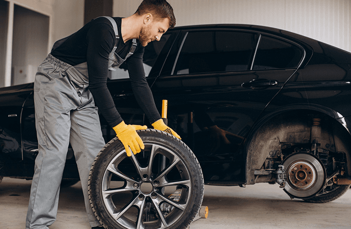 Mechanic holding a car wheel during wheel alignment service at Ten Minute Oil Change