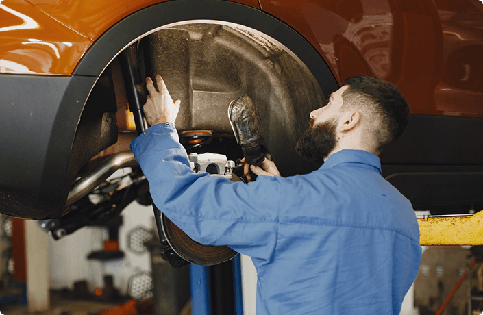 Mechanic inspecting a wheel well on a vehicle raised on a lift