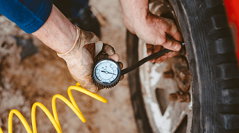Technician checking tire pressure with a gauge