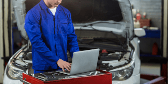 Technician performing engine diagnostics with a laptop