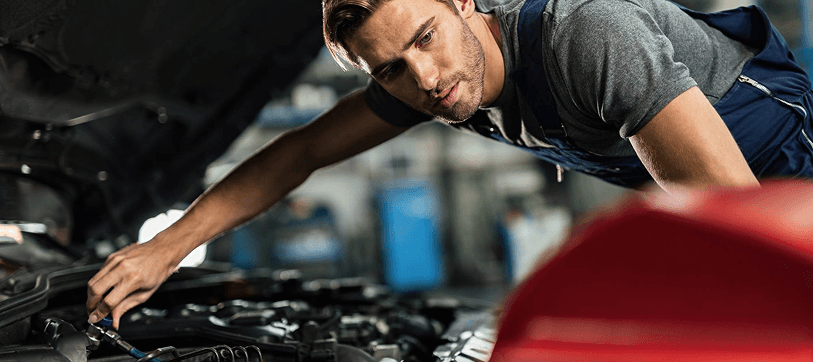 Technician performing engine diagnostic service under the hood
