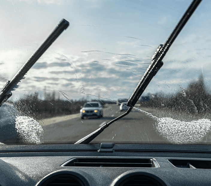 Windshield wipers clearing rain from a car windshield while driving