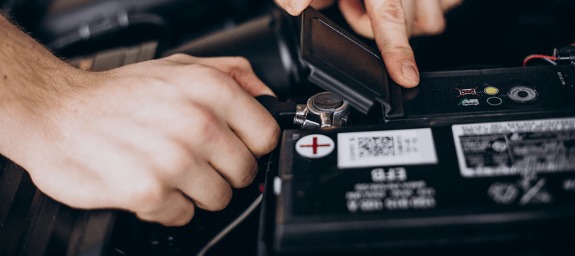 Technician working on a car battery at a charging station