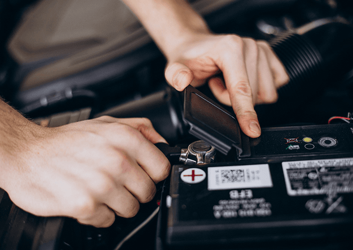 Technician inspecting a car battery in the engine bay